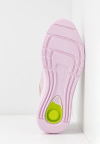 Semelle d'une basket rose clair avec une bande adhérente texturée et un élément de coussinage circulaire vert près du talon, indiquant la taille 37.