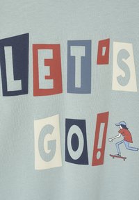 Hellblaues T-Shirt mit fettem, mehrfarbigem Text "LET'S GO!" und einer Grafik einer Person, die Skateboard fährt, gestaltet in roten und marineblauen Akzenten.