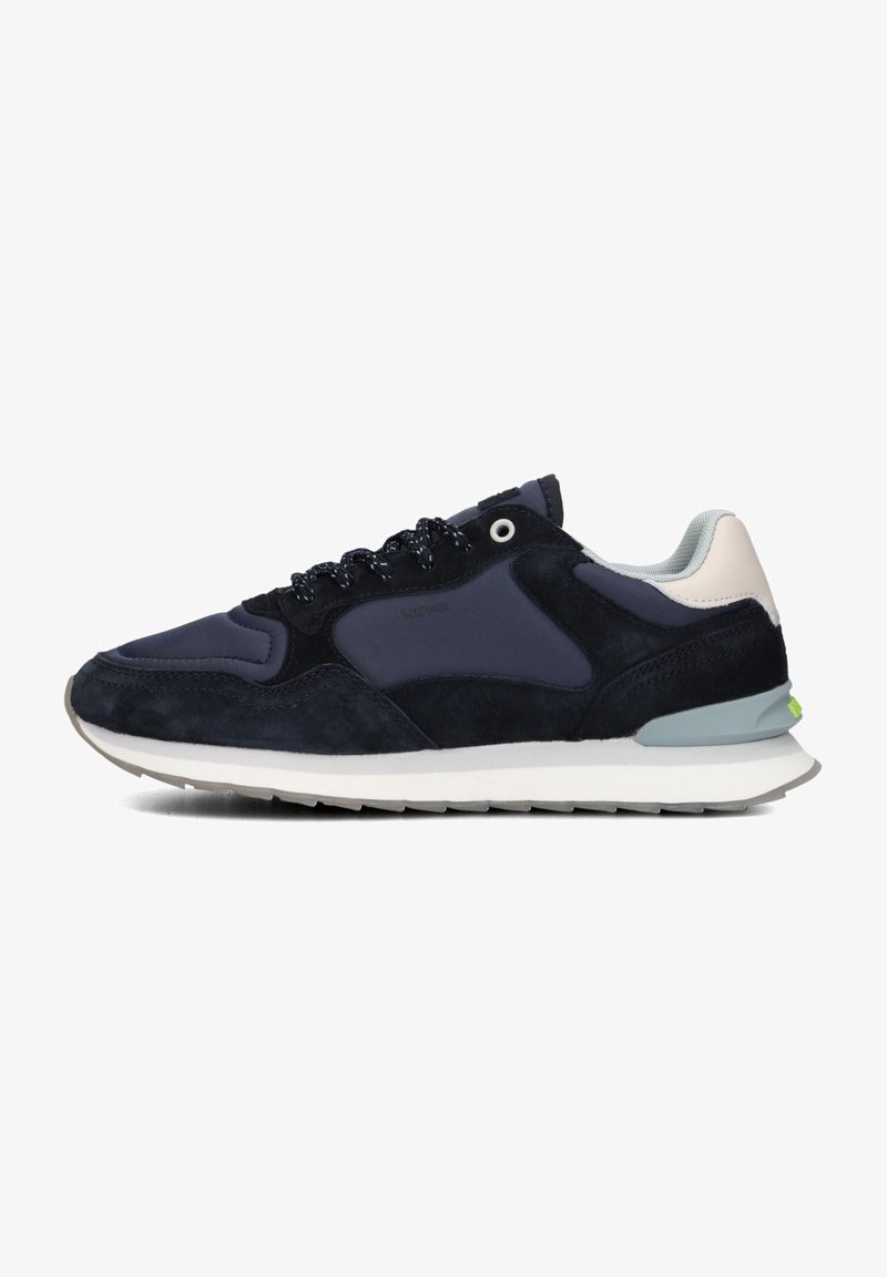 Marineblauwe sneakers met suede en mesh, voorzien van een witte tussenzool, zwarte veters en een onderscheidende groene accent aan de hiel.