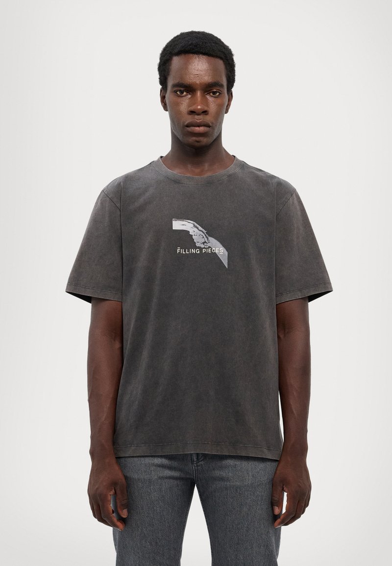 T-shirt à manches courtes en coton gris foncé avec un design imprimé sur la poitrine. Présente une coupe décontractée et un col rond, style décontracté.