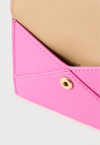 Ροζ φάκελος από συνθετικό δέρμα με μπεζ εσωτερικό. Διαθέτει γεωμετρικό σχέδιο και χρυσό κούμπωμα με πάτημα. Ομαλή υφή και καθαρές γραμμές.