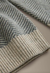 Wool scarf featuring a textured herringbone pattern in shades of grey and cream, with a ribbed edge for added detail and warmth.