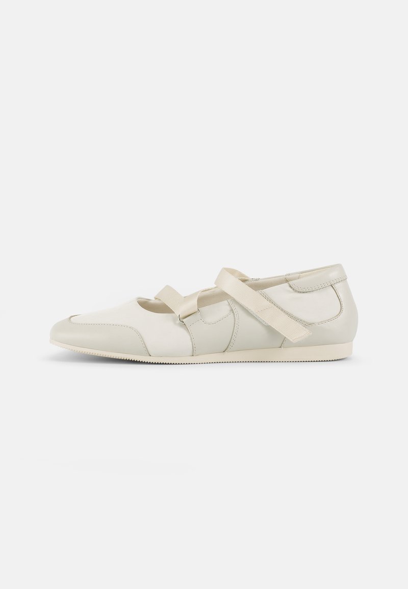 Lys beige flate sko laget av glatt lær og stoff, med to kontrasterende brede stropper og en avrundet tådesign.