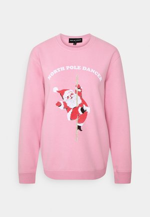 Sweatshirt rose en tissu doux avec une impression graphique d'un Père Noël sur un poteau, avec le texte "NORTH POLE DANCER" en lettres blanches en gras.