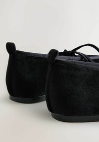 Balerini din velur negru, cu spate rotunjit, talpă subțire din cauciuc și accente din țesătură. Au un design cu șireturi și o textură moale.