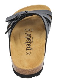 Sandale en cuir noir avec une semelle en liège, ornée de trois fines lanières et d'une boucle. L'intérieur est beige avec une texture ressemblant à du daim.