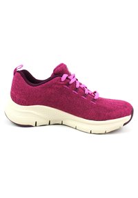 Zapatilla deportiva de punto en color púrpura con cordones rosas, parte superior texturizada y una entresuela blanca. Cuenta con una lengüeta en el talón para facilitar el uso.