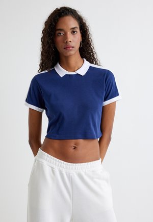 Polo de algodón cropped en color marino con cuello y puños de manga en blanco. Textura suave, corte relajado y un diseño simple.
