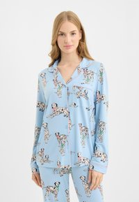 Hellblaues Pyjama-Set mit Dalmatiner-Print. Besteht aus einem Hemd mit Knöpfen und Tasche sowie einer passenden Hose, gefertigt aus weichem Stoff.