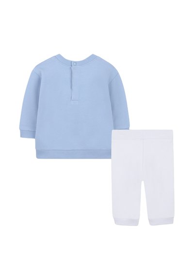 Jasnoniebieska bluzka z długim rękawem i zapięciem na guziki, białe spodnie z elastycznymi mankietami, wykonane z miękkiego materiału dla komfortu.