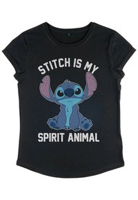T-shirt noir avec un graphique coloré du personnage Stitch et le texte "STITCH EST MON ANIMAL SPIRITUEL" en lettres blanches en gras. Manches courtes.