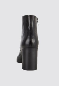 Černá kožená kotníková bota s masivním vysokým podpatkem a bočním zipem. Hladká textura a elegantní design, vhodné pro různé outfity.