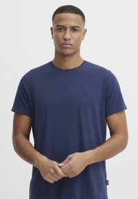 Marineblå T-skjorte med rund hals laget av myk bomull, med korte ermer og en liten svart logo på brystet i en standard avslappet passform.