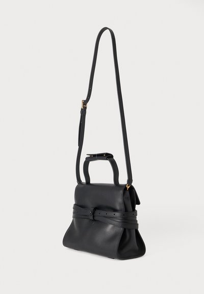 Sac à main en cuir noir avec deux poignées courtes, une longue bandoulière réglable et un détail de ceinture enveloppante sur fond blanc.