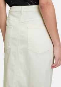 Jupe en denim clair avec poches arrière, coutures latérales et une coupe droite. Le tissu a une texture lisse et une finition soignée.