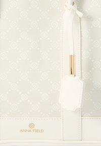 Geantă de mână albă Anna Field cu textură subtilă și modelată, logo auriu și o curea albă cu accent auriu.