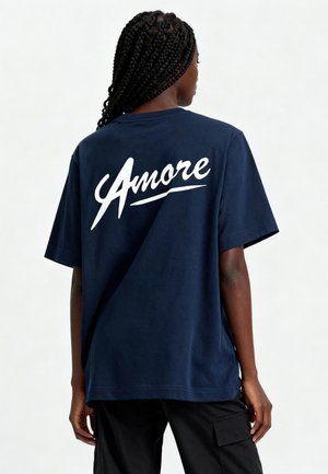 Navyblauwe katoenen t-shirt met korte mouwen en een relaxte pasvorm. "Amore" is in witte, cursieve tekst op de achterkant gedrukt. Soepele textuur.
