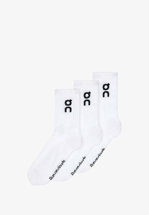 Fehér, bokáig érő zoknik pamut keverékből, bordázott textúrával. Fekete logó a oldalon, márkanevével a talpon. Három pár található.