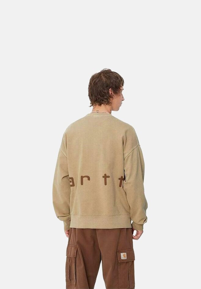 Sweatshirt beige avec une coupe décontractée et des épaules tombantes, arborant le texte marron « earth » au dos. Associé à un pantalon cargo marron.