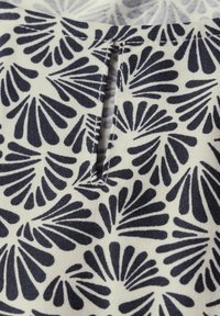 Tessuto blu navy e bianco con un motivo a foglia, caratterizzato da un piccolo dettaglio di intaglio. La trama appare liscia e intrecciata.