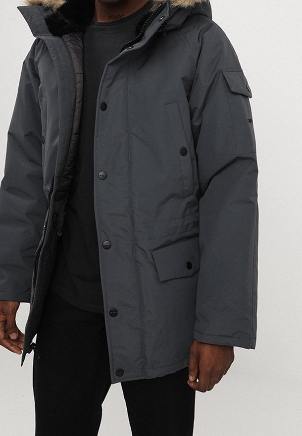 Ciemnoszara ocieplana parka z zapięciem na zamek i guziki, kaptur wyłożony futrem, kieszenie po bokach oraz strukturalny materiał. Charakteryzuje się luźnym krojem.