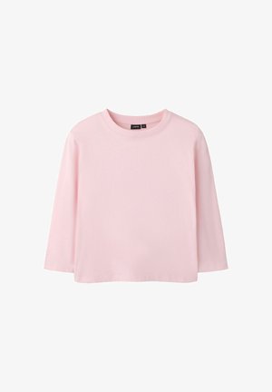 Jasnoróżowa koszulka z długim rękawem i okrągłym dekoltem, o luźnym kroju, z czarną metką od wewnętrznej strony kołnierza.