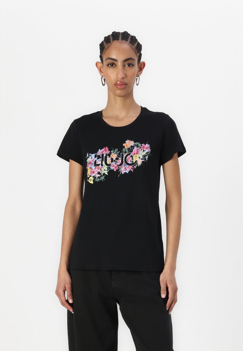 Black t-shirt with short sleeves featuring a floral design in pink, yellow, and green. Round neckline, soft fabric with a relaxed fit.