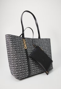 Grande borsa tote nera con motivo del logo DKNY, dotata di manici in pelle nera e di una pochette nera rimovibile. Texture liscia, forma strutturata.