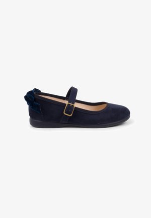 Navy blue suede ballet flat with a flat rubber sole, round toe, and a decorative velvet bow on the back. Adjustable strap with gold buckle.