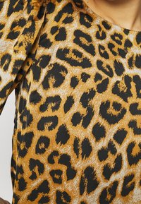 Leopard print fabric featuring a gold and black color scheme, with distinct textured spots on a smooth background.