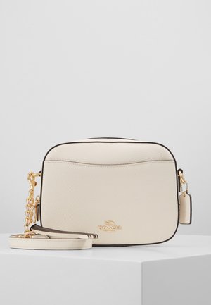 Lille cremefarvet læder crossbody taske med guldkæde-strop og Coach-logo på forsiden, vist på en hvid overflade.