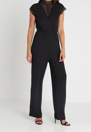 Zwarte jumpsuit met een hoog halsline met kantafwerking en korte mouwen. Verticale ribstructuur, wijde pijpen en een aansluitende taille.
