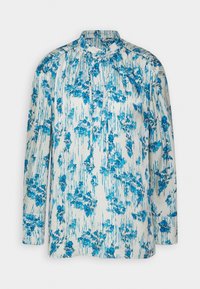 Blouse à manches longues avec une base blanche ornée de motifs floraux bleus, en tissu texturé, dotée d'un col montant et de détails de patte de boutonnage.