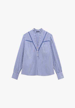Niebieska i biała bluzka w paski, z długimi rękawami, wysokim dekoltem i fałdami z przodu. Posiada ozdobne niebieskie wykończenie i trzy guziki.