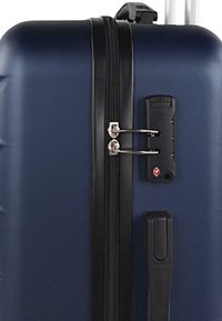 Maleta rígida de color navy con superficie texturizada, cremallera negra y cerradura aprobada por la TSA. Cuenta con un asa retráctil para un transporte fácil.