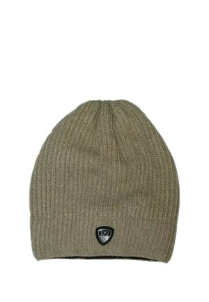 Cappello beige a coste lavorato a maglia con una piccola toppa nera a forma di scudo al centro davanti.