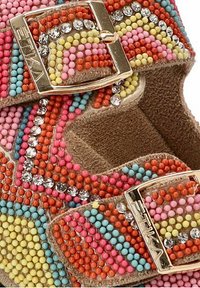 Sandalias de cuentas coloridas con base de ante, que presentan una mezcla de cuentas rosas, naranjas, azules y amarillas, y hebillas metálicas con acentos de cristal.