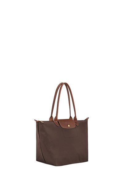 Brown tote bag with long leather handles and a flap secured by a gold button, standing upright on a white background.