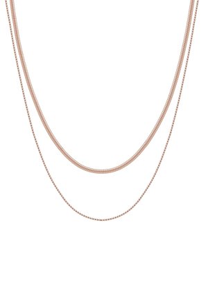 Deux chaînes délicates en or rose avec des styles de maillons différents, superposées sur un fond blanc.