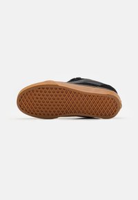 Svart sneaker med en strukturerad svart ovandel och en gummisula med diamantmönster för grepp.