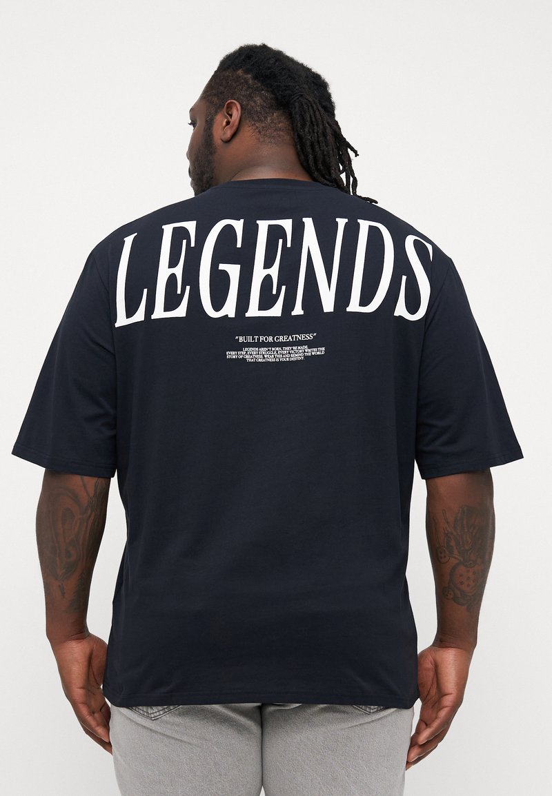 Navy blue short-sleeve t-shirt featuring large white "LEGENDS" text on the back and smaller text below. Soft fabric with a relaxed fit.