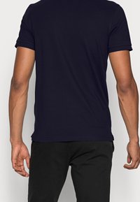 Navyblå t-shirt med kort ärm i bomull, med en slät yta, rund halsringning och uppvikta ärmslutar.