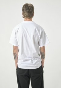 Weißes Baumwoll-T-Shirt mit kurzen Ärmeln, Rundhalsausschnitt und lässiger Passform. Die Rückansicht zeigt eine glatte Textur und keine sichtbaren Logos oder Muster.