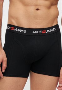 Мъжки торс, носещ черни боксерки Jack & Jones с лого на колана и видими шевове.