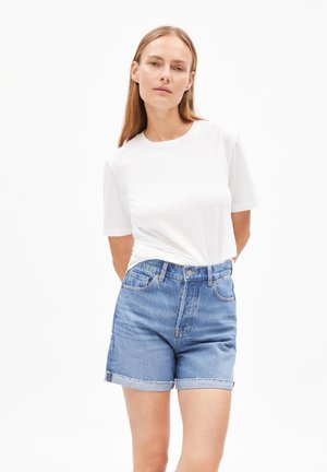 White short-sleeve t-shirt paired with light blue denim shorts featuring a frayed hem and a high-waisted cut. Simple, casual design.