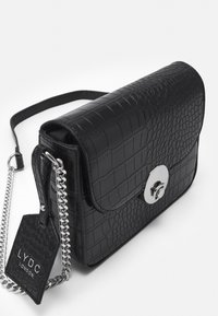 Borsa a tracolla in finta pelle nera con effetto coccodrillo, dotata di fibbia circolare in argento e tracolla a catena, caratterizzata da un'etichetta con logo.