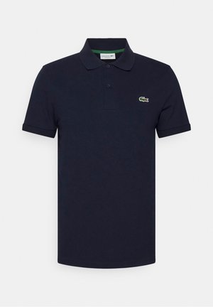 Polo bleu marine à manches courtes avec patte à deux boutons et logo crocodile vert sur la poitrine gauche sur fond blanc.
