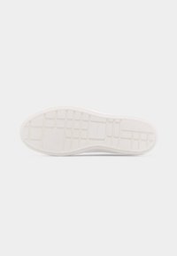 Λευκή σόλα παπουτσιού με μοτίβο πέλματος σε σχήμα πλέγματος και ορθογώνιες ενότητες σε απλό ανοιχτό γκρι φόντο.