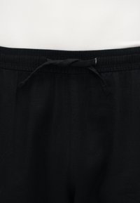 Μαύρο παντελόνι με ελαστική μέση και ανοιχτό ύφασμα κορδόνι, σε λευκό φόντο.