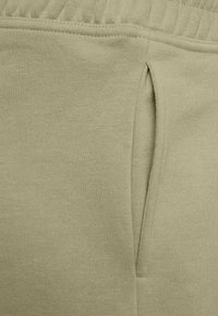 Light green sweatpants with a textured knitted fabric, featuring an elastic waistband and a side pocket detail.